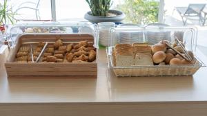 two trays of different types of bread and pastries on a counter at Akti Dimis Hotel in Tigaki