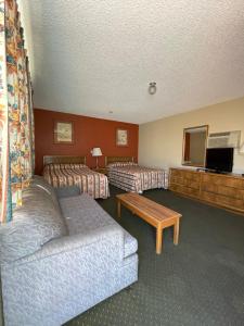 une chambre d'hôtel avec deux lits et un canapé dans l'établissement Howard Johnson by Wyndham Ridgecrest, CA, à Ridgecrest