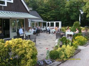 un grupo de personas sentadas en mesas en un jardín en De Spaarbankhoeve en Fluitenberg