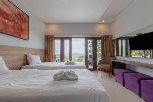 a hotel room with two beds and a television at Mandhasativa Homestay in Singaraja