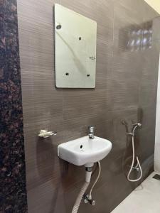 La salle de bains est pourvue d'un lavabo et d'un miroir mural. dans l'établissement Hotel Laxminarayan Niwas, à Pune