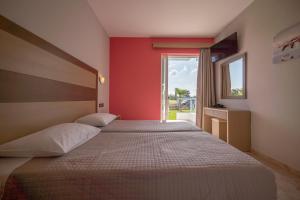 two beds in a room with red walls and a window at Akti Dimis Hotel in Tigaki