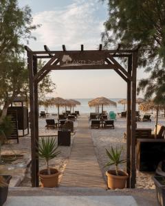 een houten promenade op het strand met tafels en parasols bij Akti Dimis Hotel in Tigaki
