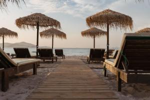 a wooden pathway to the beach with umbrellas and chairs at Akti Dimis Hotel in Tigaki