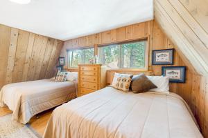 two beds in a room with wood paneling at Fernwood in Shaver Lake