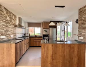 a large kitchen with wooden cabinets and a counter top at Casa , Dílar, Granada con jardin y piscina in Dílar