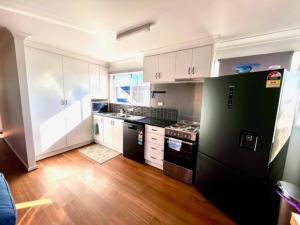a kitchen with white cabinets and black appliances at Clarendon Cottage, near Lowood , Fernvale, right on the BVRT in Clarendon