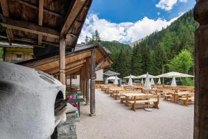 um grupo de mesas de madeira e guarda-sóis num pátio em Enzianhütte em San Giuseppe in Anterselva