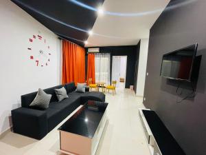 a living room with a black couch and a clock at New Park Resort in Mahajanga
