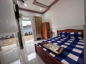 a bedroom with a bed with a blue and white blanket at Motel Khánh Vy in Bao Loc