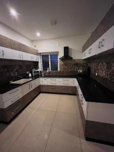 a large kitchen with white cabinets and black counter tops at Mellow Mount Private Homestay in Ooty