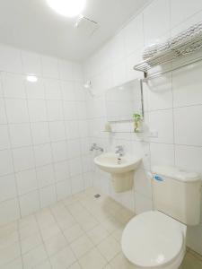 a white bathroom with a toilet and a sink at Qianshun Homestay in Xingang