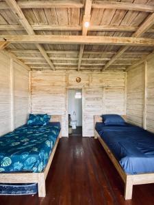 Duas camas num quarto com paredes de madeira em Dikaloha Surfschool and Stay em Airsatang