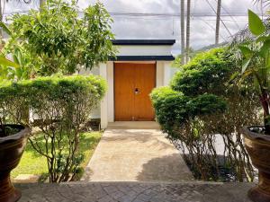 a house with a wooden door in a garden at Siam Jewel - Private pool villa in Bang Tao in Bang Tao Beach