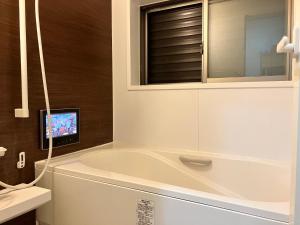 La salle de bains est pourvue d'une baignoire et d'une télévision murale. dans l'établissement 新規OPEN8割！1棟貸切・10名可能！秋葉原まで13分、新宿まで32分／スカイツリー近く, à Tokyo 20 autres photos