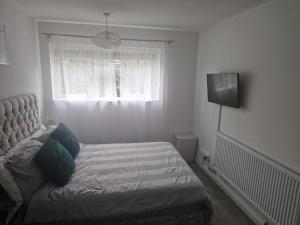 Immaculate 1-Bed Apartment in Woodford Green في وودفورد غرين: غرفة نوم صغيرة بها سرير ونافذة