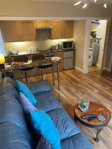 a living room with a blue couch and a kitchen at Glasphein Annex Inverness in Culloden