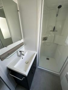 a white bathroom with a sink and a shower at Camping 4 étoiles Le bois dormant in Saint-Jean-de-Monts