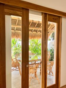 eine offene Tür zu einer Terrasse mit Stühlen und Tischen in der Unterkunft Casa Flores in Kuta Lombok