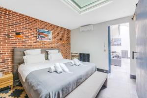- une chambre avec un grand lit et un mur en briques dans l'établissement Les appartements de l'atelier paris 15, à Paris