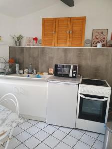 een keuken met een wit fornuis en een magnetron bij La Maison de Jeanne in Lesparre-Médoc