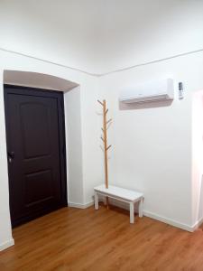 um quarto branco com uma porta preta e um banco em Antica Sicilia Luxury em Regalbuto