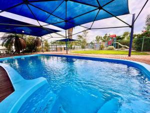 ein blauer Pool mit einem blauen Sonnenschirm in der Unterkunft Renovated Managers Apartment in South Hedland
