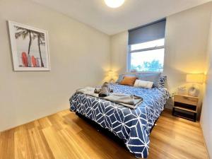 ein Schlafzimmer mit einem Bett mit blauer Decke und einem Fenster in der Unterkunft Renovated Managers Apartment in South Hedland