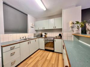 une cuisine avec des placards blancs et un comptoir vert dans l'établissement Renovated Managers Apartment, à South Hedland