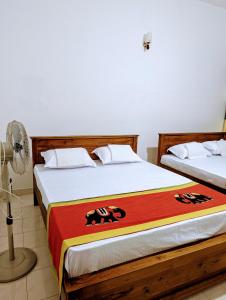 two beds in a room with a fan at Moon Water's Edge in Kandy