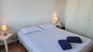 ein Schlafzimmer mit einem weißen Bett mit zwei blauen Handtüchern darauf in der Unterkunft Vista Bella House in Sanremo