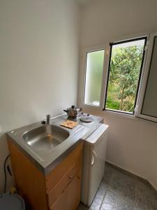 una pequeña cocina con fregadero y ventana en Casa De Blue Studios & Apartments, en Lourdata