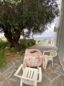 a table and chairs with a table and a tree at Casa De Blue Studios & Apartments in Lourdata