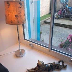 a cat figurine sitting on a table next to a lamp at Hideaway cottage - Studio ground floor with toilet and sink in Sandgate