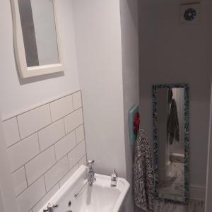 a bathroom with a tub and a sink and a mirror at Hideaway cottage - Studio ground floor with toilet and sink in Sandgate