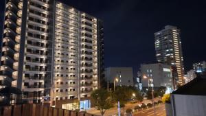 een hoog gebouw in een stad 's nachts bij Guesthouse Yours in Osaka