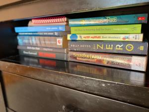 a stack of books sitting on a shelf at The Cozy Hutt Home in Upper Hutt