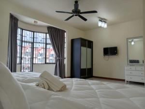 BUTTERWORTH RAJA UDA RAYA HOMESTAY في بترورث: غرفة نوم مع سرير أبيض كبير مع مروحة سقف