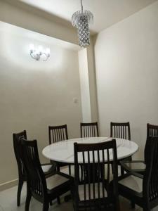 BUTTERWORTH RAJA UDA RAYA HOMESTAY في بترورث: غرفة طعام مع طاولة بيضاء وكراسي