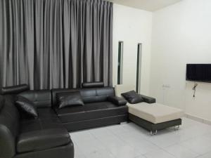 a living room with a black leather couch and a tv at BUTTERWORTH RAJA UDA RAYA HOMESTAY in Butterworth