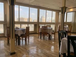 a dining room with tables and chairs and large windows at Holidays Express Hotel in Cairo