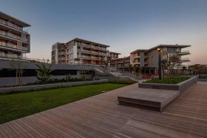 a park with buildings and a bench on a boardwalk at Luxury Beach Getaway@Coral Point in Sibaya