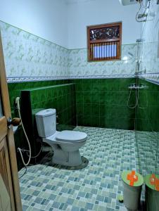 La salle de bains est pourvue de toilettes et de carrelage vert. dans l'établissement Moon Water's Edge, à Kandy