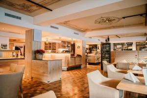 a restaurant with white chairs and tables and a kitchen at Macher's Landhotel in Sankt Jakob in Defereggen
