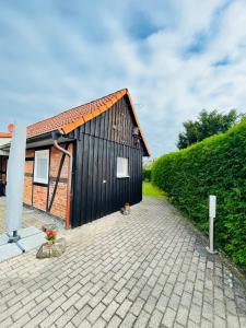 a small black building with a brick driveway at Sanders Ferienhaus in Winsen