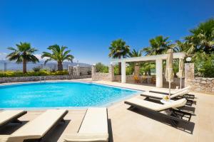 a swimming pool with chaise lounge chairs and a villa at Epavlis Akrotiri in Chania