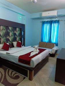 een slaapkamer met 2 bedden, een bank en blauwe muren bij Hotel Nirmala Inn in Jamūi