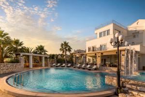 a pool in front of a building with palm trees at Epavlis Akrotiri in Chania