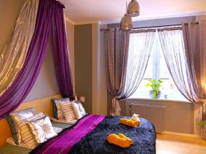 a bedroom with purple curtains and a bed with two animals on it at Silwer ROOM in Kraków