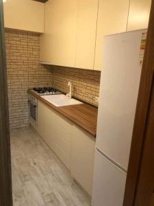 a kitchen with a white refrigerator and a sink at Apartment George in Kutaisi